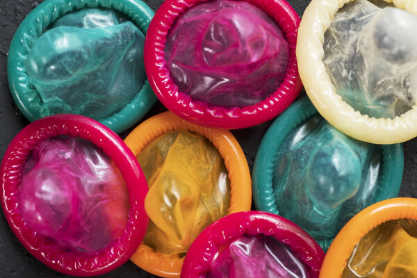 Safe sex concept. Top view of messy colorful condoms over table