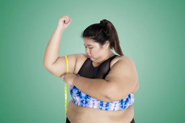 亚洲脂肪妇女穿着运动衫的图片 同时测量她的上臂与卷尺 — 图库照片