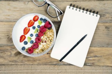 İş kahvaltı boş not defteri, gözlük ve bir kase yoğurt masada