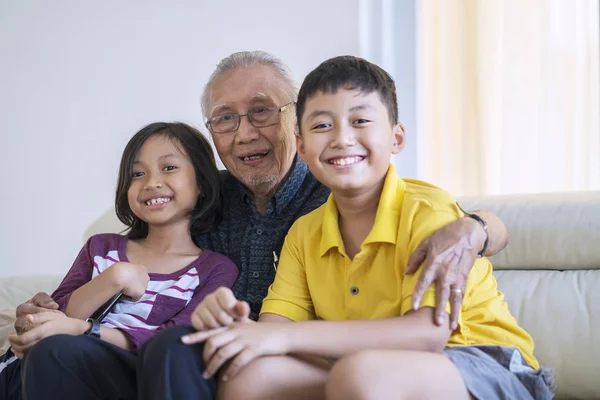 Mutlu Yaşlı Adam Torunları Evde Oturma Odasında Otururken Kameraya Gülümseyen — Stok fotoğraf