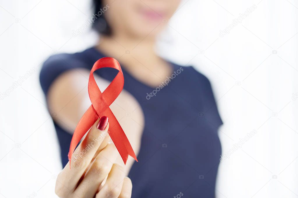 Closeup of woman hand holding a world AIDS day awareness ribbon in the studio