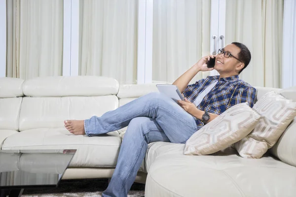 Junger Mann Spricht Mit Smartphone Während Ein Digitales Tablet Hause — Stockfoto