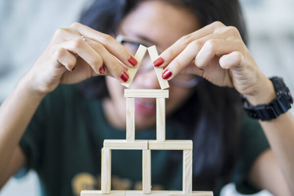 Dream house concept with a young woman playing wooden blocks and arrange a house