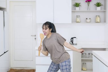 Tahta bir spatula ile evde mutfakta yemek yaparken şarkı Genç Asyalı kadın görüntüsünü