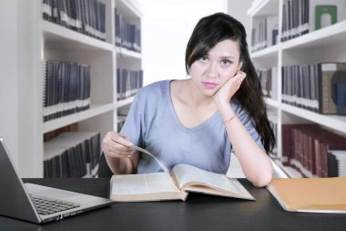 Kütüphanede masada kitap okurken kameraya arayan güzel bayan üniversite öğrenci portresi