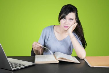Masanın üzerine bir kitap okuma ve kameraya bakıyor güzel bayan üniversite öğrencisi. Yeşil ekran arka plan ile vurdu
