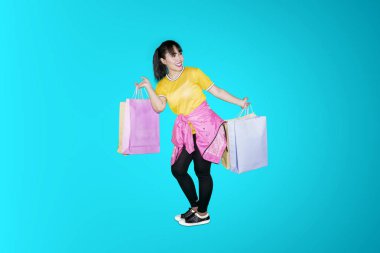Alışveriş torbaları tutarken stüdyoda dans mutlu genç kadın portresi