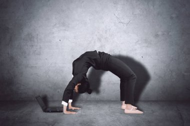 Genç balerin köprü egzersiz yapmak ve bir dizüstü bilgisayar ile çalışma sırasında takım elbise