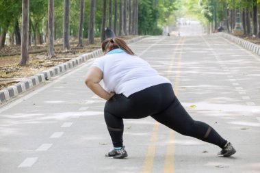 Arkadan Görünüş kilolu kadın yolda bir egzersiz yapmadan önce bacaklarını germe 