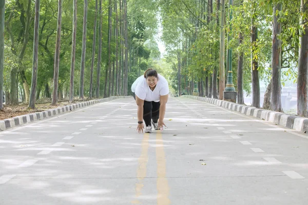 道路にひざまずいている間を実行する準備ができている若い肥満女性の画像 — ストック写真