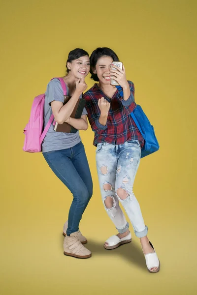 Tam Uzunlukta Iki Kadın Üniversite Öğrencilerinin Smartphone Iyi Haber Okurken — Stok fotoğraf