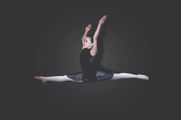 年轻芭蕾演员在黑暗背景下跳优雅舞蹈的照片 — 图库照片