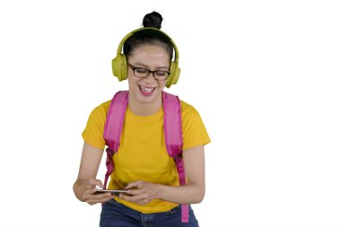 Stüdyoda bir akıllı telefon dinleme müzik süre oynayan Bayan üniversite öğrencisi resmini