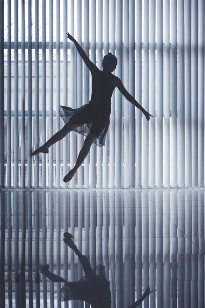 Silhouette of a graceful ballet dancer jumping and dancing near the window