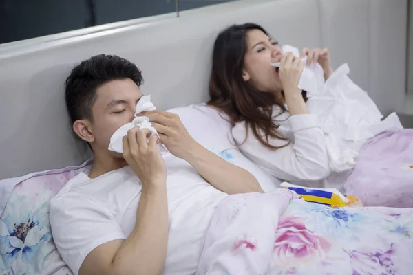 生病的亚洲夫妇躺在床上用纸巾打喷嚏的肖像 — 图库照片