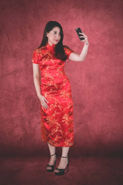 Güzel Kız Cheongsam Elbise Kırmızı Arka Planda Giyerken Selfie Fotoğraf — Stok fotoğraf