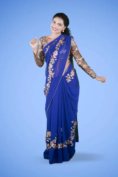 Full length of pretty Indian woman wearing a blue saree clothes in the studio with blue background