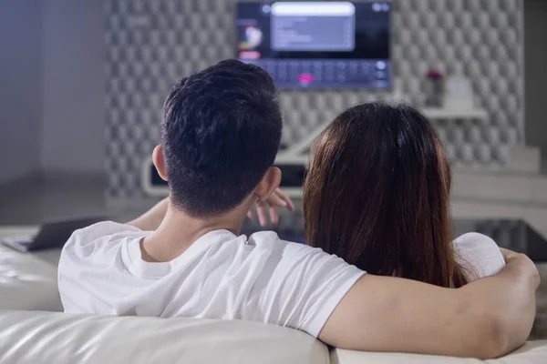 自宅でリラックスしながらテレビを見て若いカップルの背面図 — ストック写真