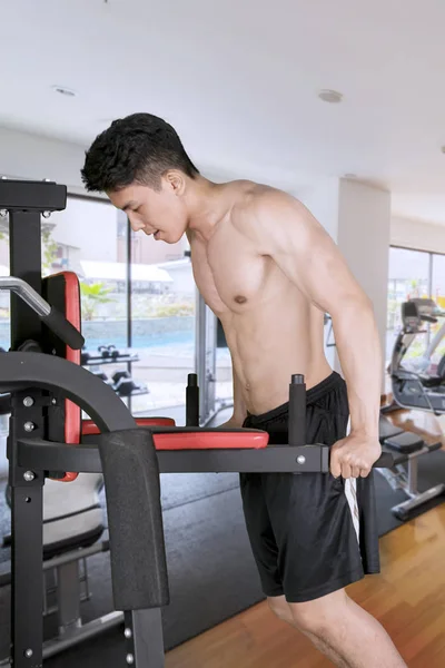 Portrait of young muscular man doing a workout with fitness equipment in the gym center