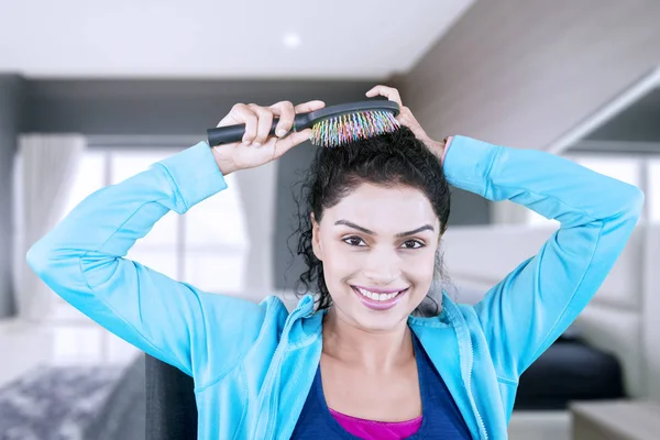 Imagem Jovem Está Penteando Cabelo Enquanto Está Sentada Quarto — Fotografia de Stock