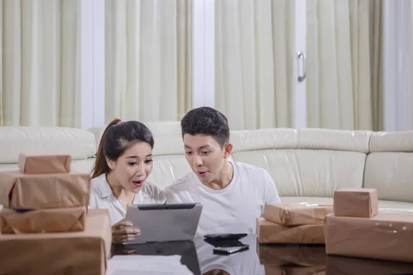 Selling Online concept. Happy young couple looking at digital tablet with cardboard on table for online marketing packing box delivery.