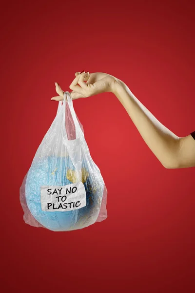 Concept of save earth from plastic waste pollution. Young woman hands holding an earth globe in a plastic bag with text of say no to plastic