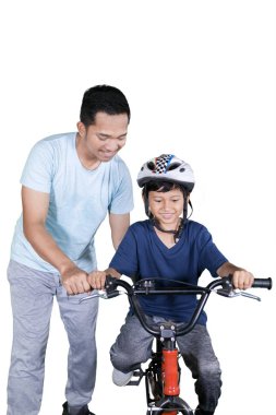 Beyaz arka plan üzerinde izole Studio, Bisiklete binmek için oğlunu rehberlik genç adam portresi 