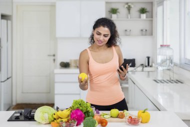 Mutfakta salata hazırlanırken bir cep telefonu kullanarak güzel bir kız portresi