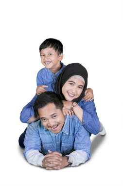 Müslüman aile kameraya birlikte yerde, beyaz arka plan üzerinde izole yatıyor iken gülümseyen portresi