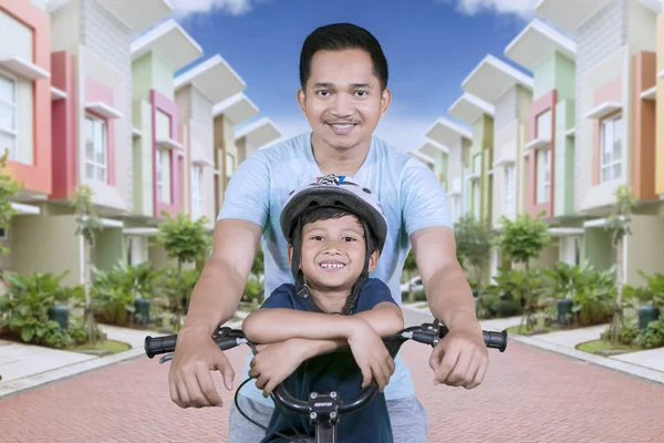 小男孩和父亲在路上骑自行车时对着镜头微笑的画面 — 图库照片