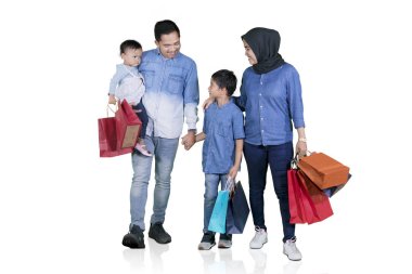 Genç Asyalı aile birlikte beyaz arka plan üzerinde izole stüdyoda yürürken alışveriş çantaları taşırken resmini