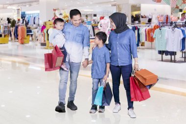 Müslüman aile birlikte çarşıda yürürken alışveriş çantaları taşırken resmini