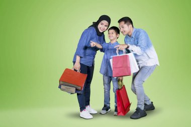 Stüdyoda ailesi ile alışveriş yaparken mutlu küçük çocuk bir şey işaret resmi