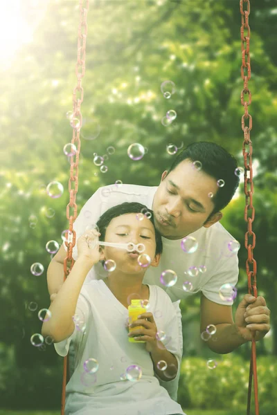 Der Kleine Junge Pustet Mit Seinem Vater Seifenblasen Während Auf — Stockfoto