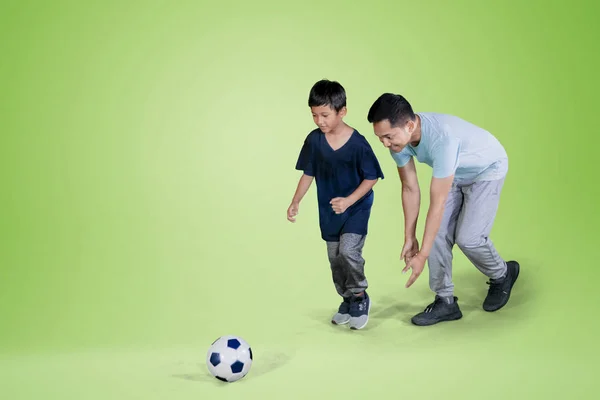 年轻人和儿子在演播室里用绿屏踢足球的照片 — 图库照片