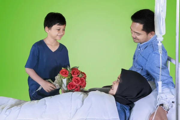 小男孩拿着一束花 而访问他的母亲与他的父亲在工作室与绿屏 — 图库照片