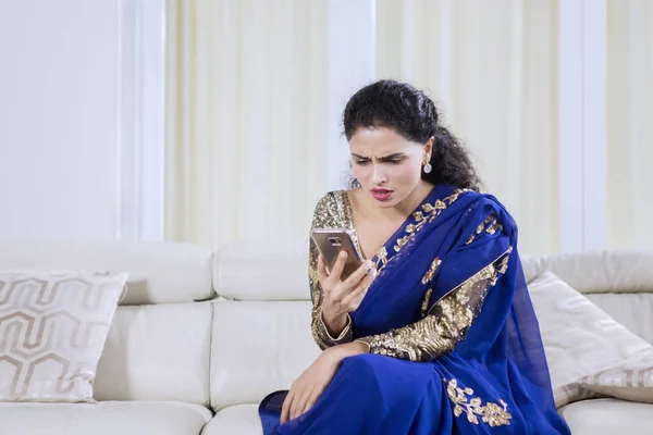 印度年轻女子在家中使用手机时显得很困惑 — 图库照片