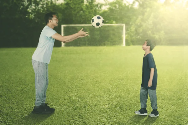 サッカー場で遊んでいる間彼の息子にボールを投げる父の肖像 — ストック写真