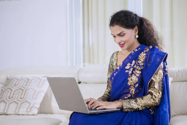 美丽的印度妇女穿着蓝色的萨里衣服 而与笔记本电脑在家里工作 — 图库照片