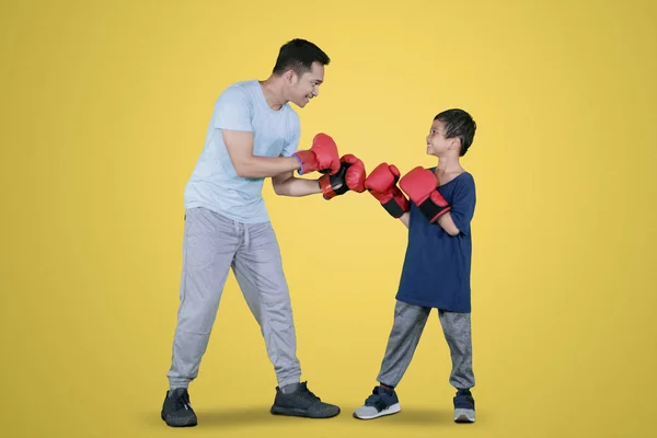 スタジオでボクシングの練習をしながら 彼の息子と戦う準備ができている若い男の写真 — ストック写真