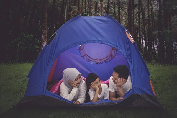 Picture of young parents camping in the forest while lying with their son in the tent
