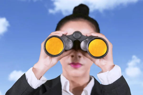 青い空を背景に立っている間双眼鏡カメラを見て女性起業家のクローズ アップ — ストック写真