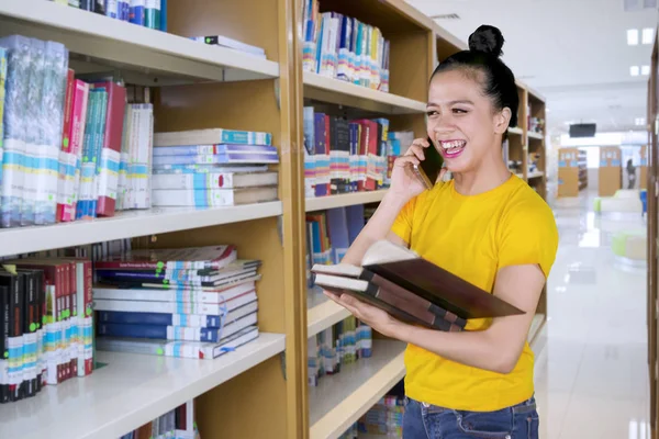 Boldog Női Főiskolai Hallgató Tanulmányai Során Könyvtár Mobiltelefonon Beszél — Stock Fotó