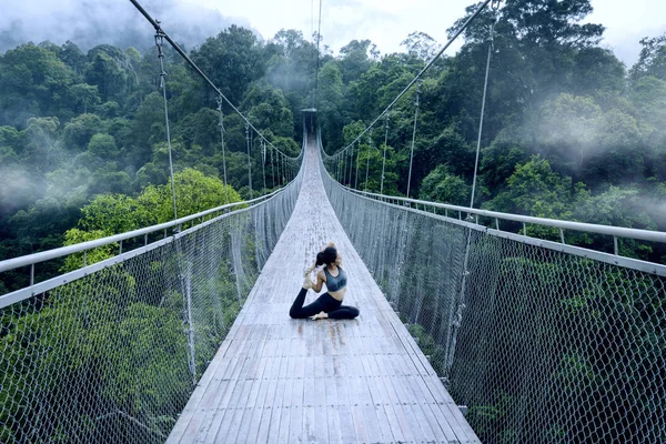 スポーツウェアを着てその場グヌン吊り橋でヨガのエクササイズをしながらアジアの女性の肖像画 — ストック写真