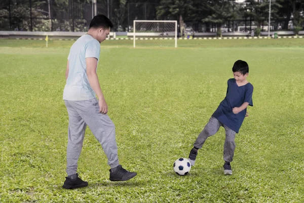 フィールドでの試合中にボールを彼の父に渡す小さな少年の写真 — ストック写真
