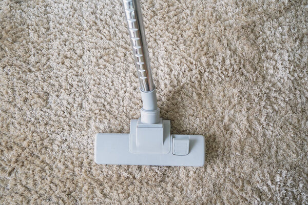 Top view of a modern vacuum cleaner being used while vacuum uming white carpet
