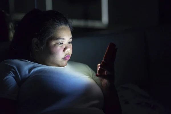 夜寝る前に携帯電話を使用しながらベッドの上に座っての肥満女性のクローズ アップ — ストック写真
