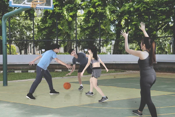 Group of teenagers playing basketball together while doing a friendly match in the basketball court