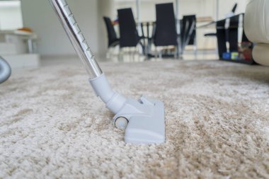 Beyaz halı üzerinde kir kaldırma sırasında kullanılan bir elektrikli süpürge, yakın çekim