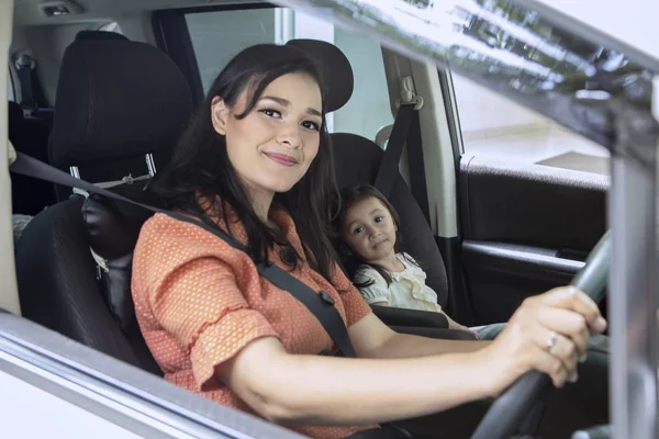 彼女の娘が付いている車を運転している間は カメラで笑顔の若い母親 — ストック写真